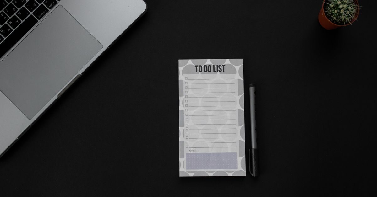 Handwritten essay outline on a notepad next to a pen and laptop