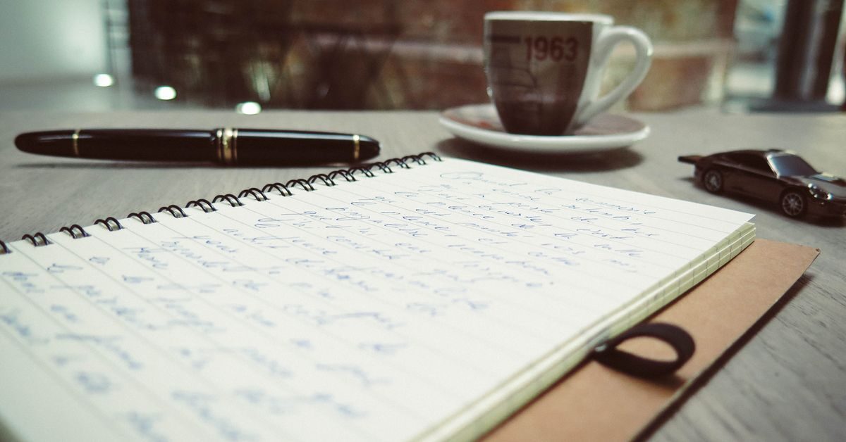 How to write a research paper with notes, coffee and a laptop on a warm desk